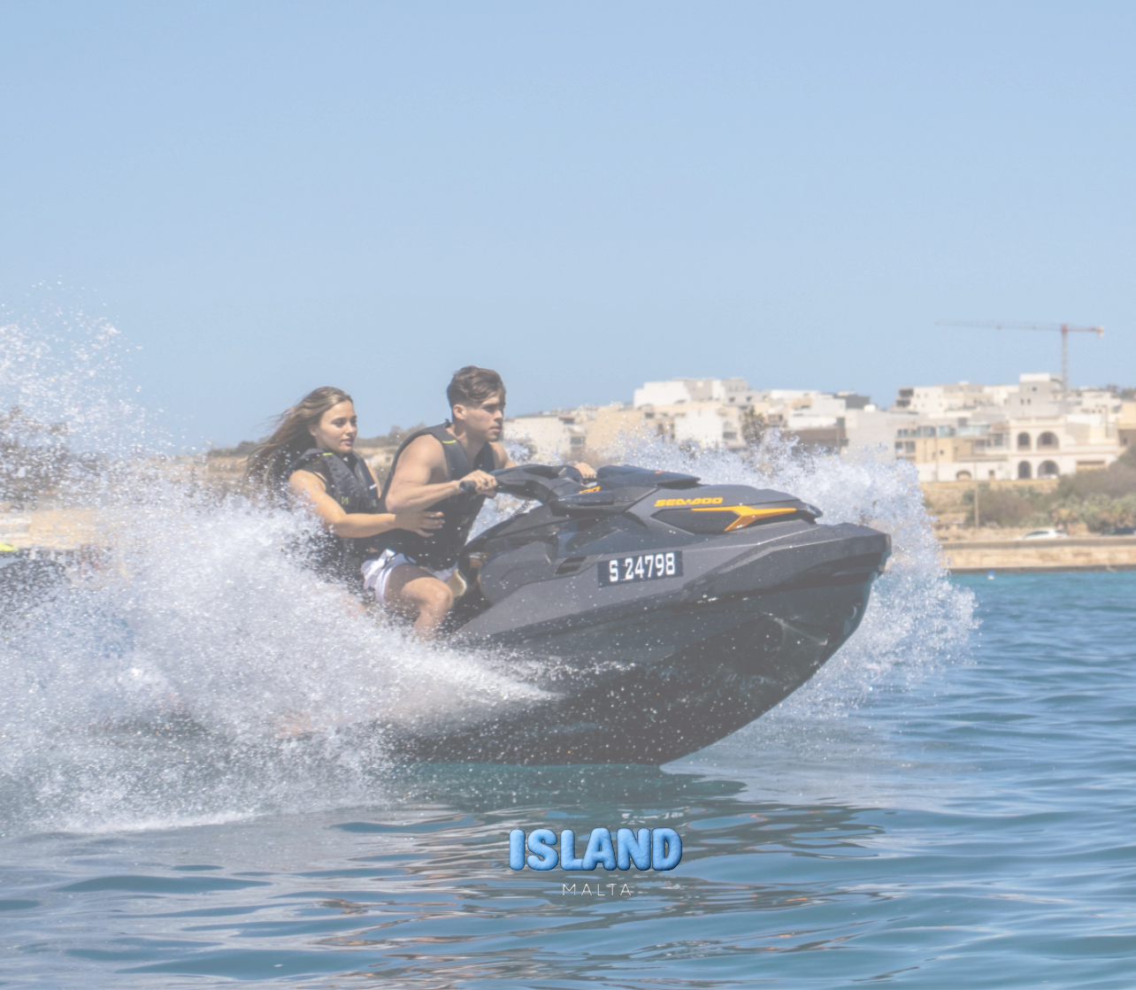 Two people riding a jet ski in Malta, spraying water with the coastline in the background